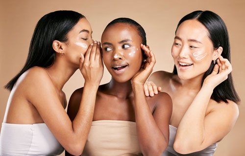 Three women applying skincare product to their faces