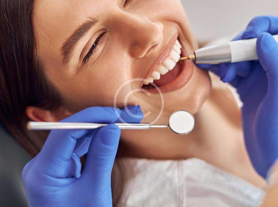 Dentist performing teeth-whitening procedure on a woman