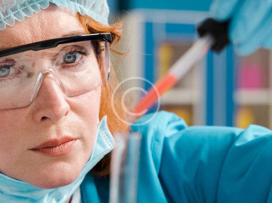 Red-haired medical scientist examining red liquid in a syringe